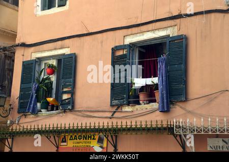 Washing Hanging on Clothes Line Outside Green Shuttered Windows Above Shops in the Old Town of Corfu, Greece, EU. Stock Photo