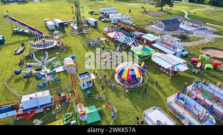 Aerial View of Bustling Carnival with Ferris Wheel and Rides at Golden Hour Stock Photo
