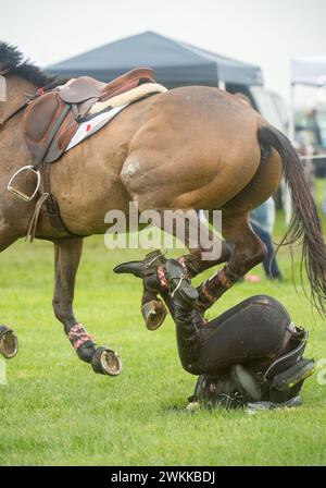 Fallen female horseback rider on ground wearing protective vest  expands when rider falls and releases valve protecting riders body in competition Stock Photo