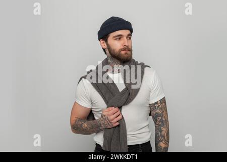 Handsome fashionable hipster man with a knitted hat in a white T-shirt with a sweater on a white background in the studio Stock Photo