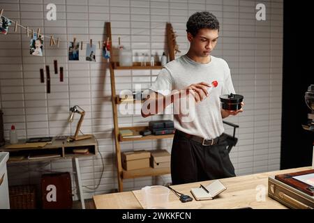 skilled african american photographer pouring chemical solution into film developing tank Stock Photo