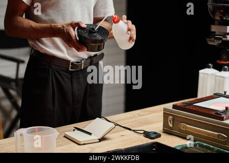cropped photo of african american photographer pouring chemical solution into film developing tank Stock Photo