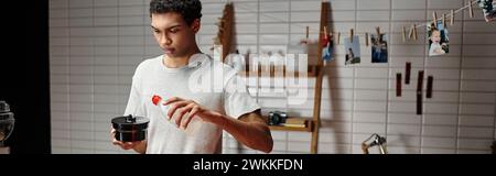 banner of african american photographer pouring chemical solution into film developing tank Stock Photo