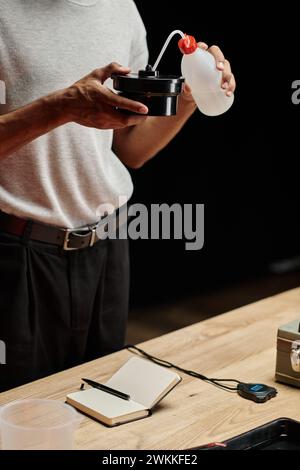 cropped shot of african american photographer pouring chemical solution into film developing tank Stock Photo