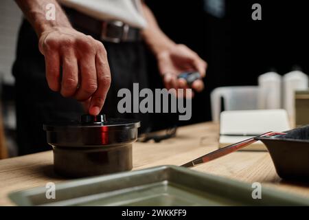 african american photographer securing a film canister lid in a darkroom, blurred timer in hand Stock Photo