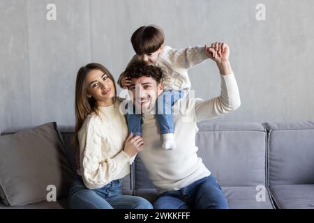 Cheerful family having fun and playing with little son while chilling together on sofa in living room Stock Photo