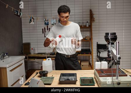 young african american photographer engaged in analog film development in a professional darkroom Stock Photo