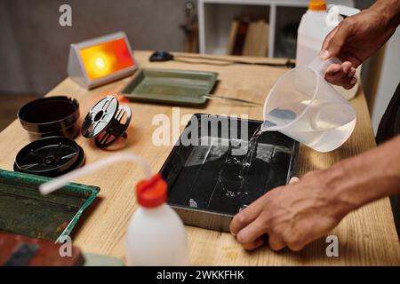 cropped photo of african american photographer pouring chemical solution for film development Stock Photo