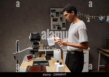 young african american man pouring chemical solution in measuring cup, analog film development Stock Photo