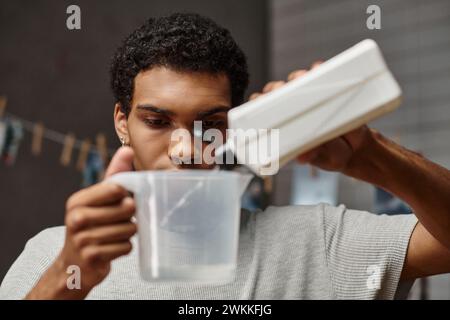 handsome african american photographer pouring chemical solution in measuring cup, film development Stock Photo
