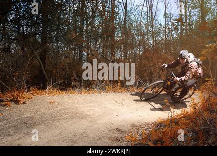 Cyclist on a gravel bike rides along a sharp turn on a trail in the forest. Extreme sport. Stock Photo