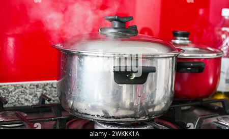 Steam or Vapour clouds rising from boiling water in saucepan on stove. Steam from pan while cooking Stock Photo