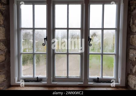 Condensation on inside of single glazed windows in wooden frame in morning Stock Photo