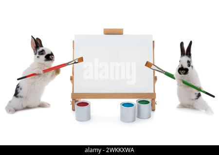 Two bunnies stand at the easel with tassels isolated on a white background. for writing your text Stock Photo