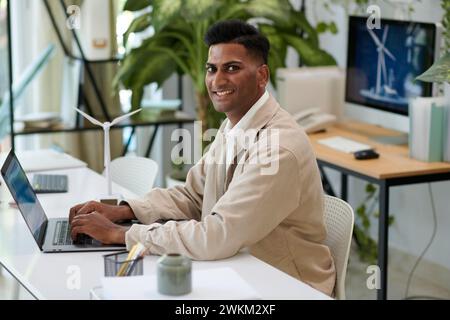 Portrait of smiling Indian wind turbine sales manager working on computer Stock Photo