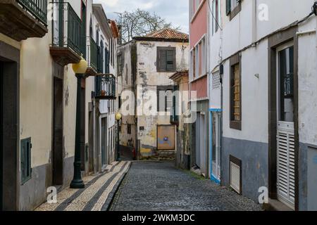A picturesque alley of historic stone buildings on a cobblestone street in the historic old town of Funchal, Portugal, on the Canary Island of Madeira Stock Photo