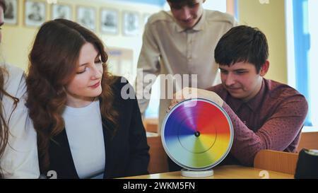 Students in physics class spin Newton's multicolored disk. Stock Photo