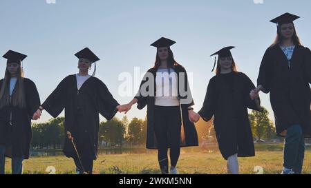 Graduate students walking through an evening meadow at sunset. Stock Photo