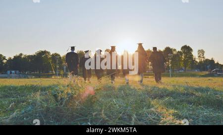 Graduate students walking through an evening meadow at sunset. Stock Photo