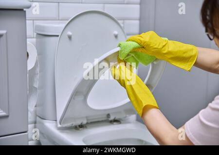 Close-up hands in protective gloves cleaning toilet in bathroom Stock Photo