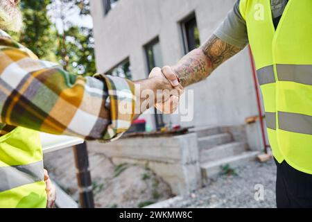 cropped view of two hardworking construction workers shaking their hands, cottage builders Stock Photo