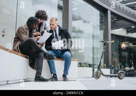 Multiracial business colleagues reviewing documents outdoors in a modern urban setting. Stock Photo