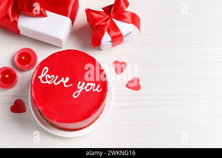 Bento cake with text Love You, gift boxes, candles and paper hearts on white wooden table, space for text. St. Valentine's day surprise Stock Photo