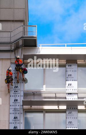 Two men climbing a building for construction work, exterior view, daytime with blue sky, Melbourne city, Australia. Stock Photo