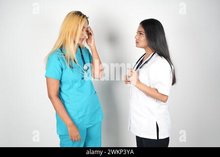 Two female medical professionals in scrubs and scrub caps having a conversation Stock Photo