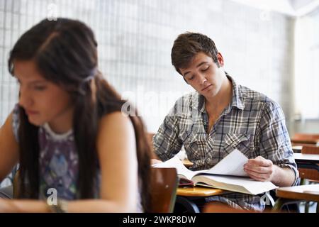 Studying, students and reading in textbook for information, test and knowledge for assignment in university. People, scholarship or concentration in Stock Photo
