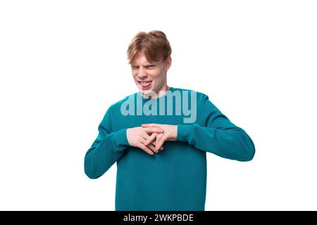 portrait of a confused young caucasian student guy with red hair dressed in a blue pullover Stock Photo