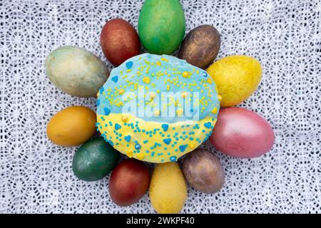 composition with multi-colored Easter eggs placed around an Easter cake sprinkled with yellow and blue glaz Stock Photo