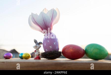 multi-colored Easter and chocolate eggs, an Easter bunny and a blooming large magnolia flower Stock Photo
