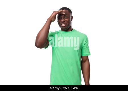 A 30-year-old smart African man dressed in a light green T-shirt is trying to remember a thought Stock Photo