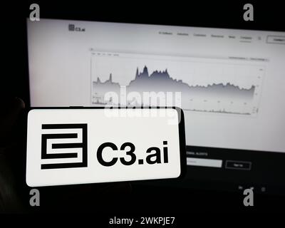 Person holding mobile phone with logo of American artificial intelligence company C3.ai Inc. in front of web page. Focus on phone display. Stock Photo