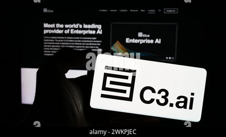 Person holding cellphone with logo of US artificial intelligence company C3.ai Inc. in front of business webpage. Focus on phone display. Stock Photo