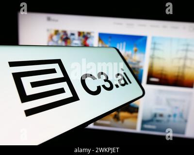 Mobile phone with logo of American artificial intelligence company C3.ai Inc. in front of website. Focus on center-left of phone display. Stock Photo