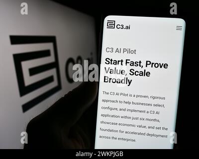 Person holding cellphone with webpage of US artificial intelligence company C3.ai Inc. in front of logo. Focus on center of phone display. Stock Photo