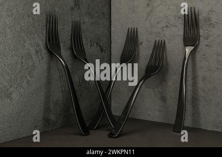 Five black plastic forks on an elegant  black slate background Stock Photo