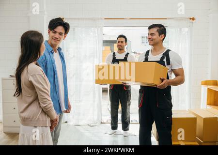 A couple receives assistance inside home from movers unloading boxes from truck. Professional Stock Photo