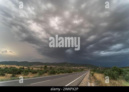 Empty road (asphalt road) through yellowish fields. Dramatic sky before rain and storm. Mammatus cumulonimbus in the sky. Landscape concept. Stock Photo