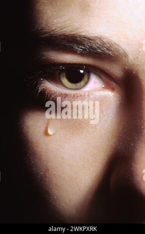 young woman crying with a single tear running down her cheek from her eye Stock Photo