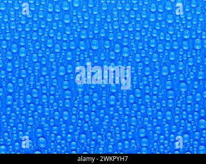 many water drops on a blue surface, a smiley face is reflected in every drop Stock Photo