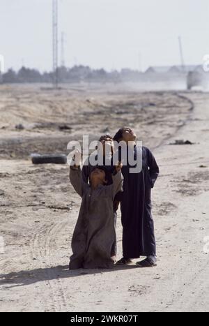 17th March 1991 On the outskirts of Safwan in southern Iraq, three Iraqi children look skywards as an American Army helicopter flies overhead. Stock Photo