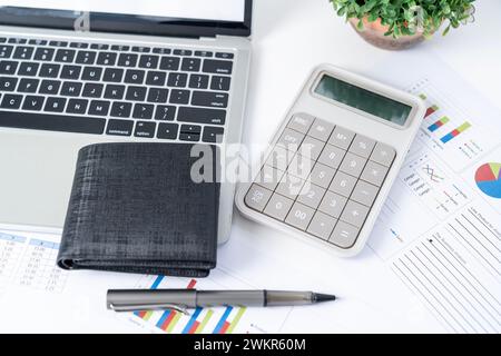 A calculator, a wallet, and a laptop computer on the work desk Stock Photo