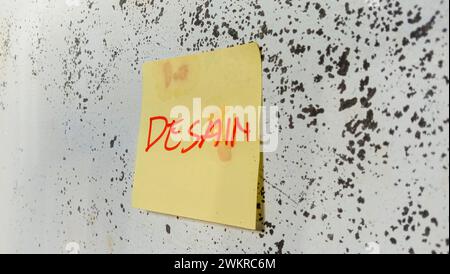 Text with the words "design" on a note pasted on the wall Stock Photo