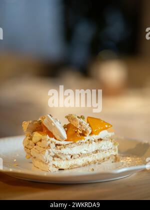 Puff layered cake with cream of cream-cheese, decorated fresh persimmons. Delicious and eye-catching piece of layered cake decorated orange persimmons Stock Photo