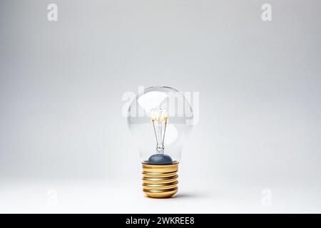 Incandescent Light Bulb Glowing Against a Neutral Background in Studio Setting Stock Photo
