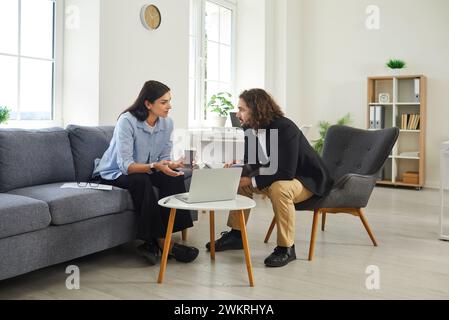 Two business people meeting in office, using laptop, drinking coffee and talking Stock Photo