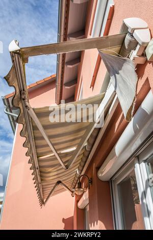 Old, messy, dirty and broken retractable awning installed on family house Stock Photo